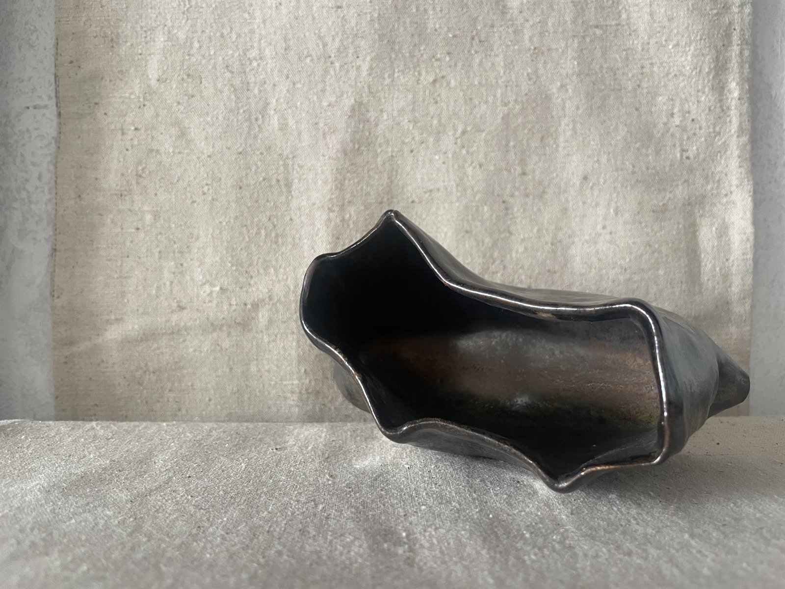 Low pinch bowl with exposed coarse clay rim on linen