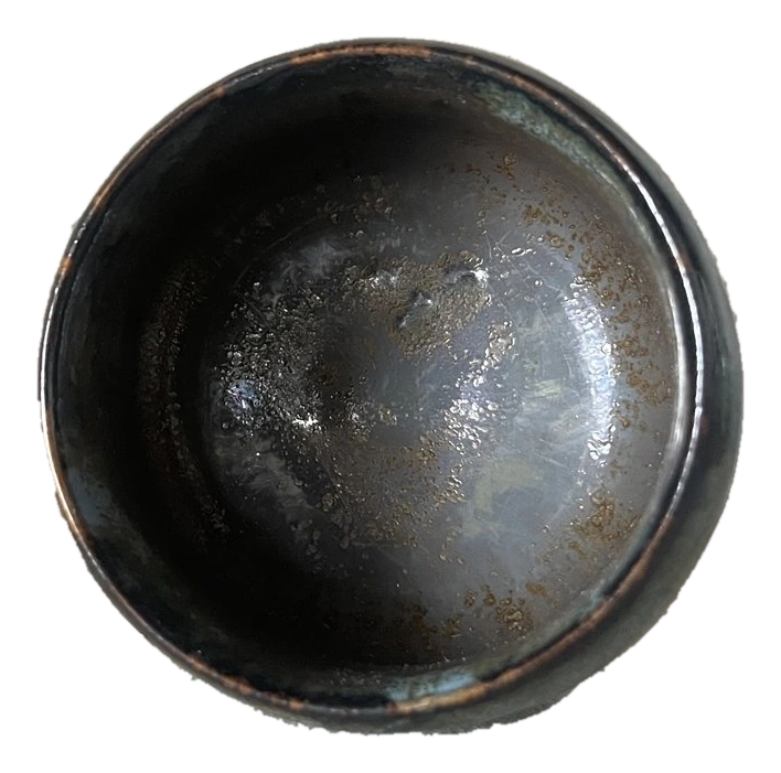 Interior of a dark circular bowl with metallic glaze pooling