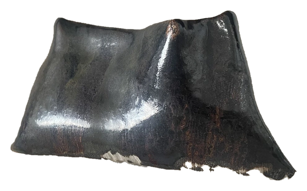 Angular dark ceramic form with exposed pale clay along its base