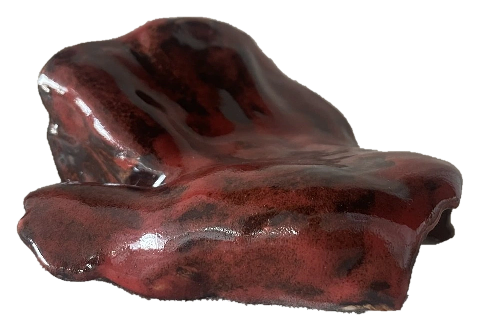 Low folded sculptural ceramic form with a deep red glaze