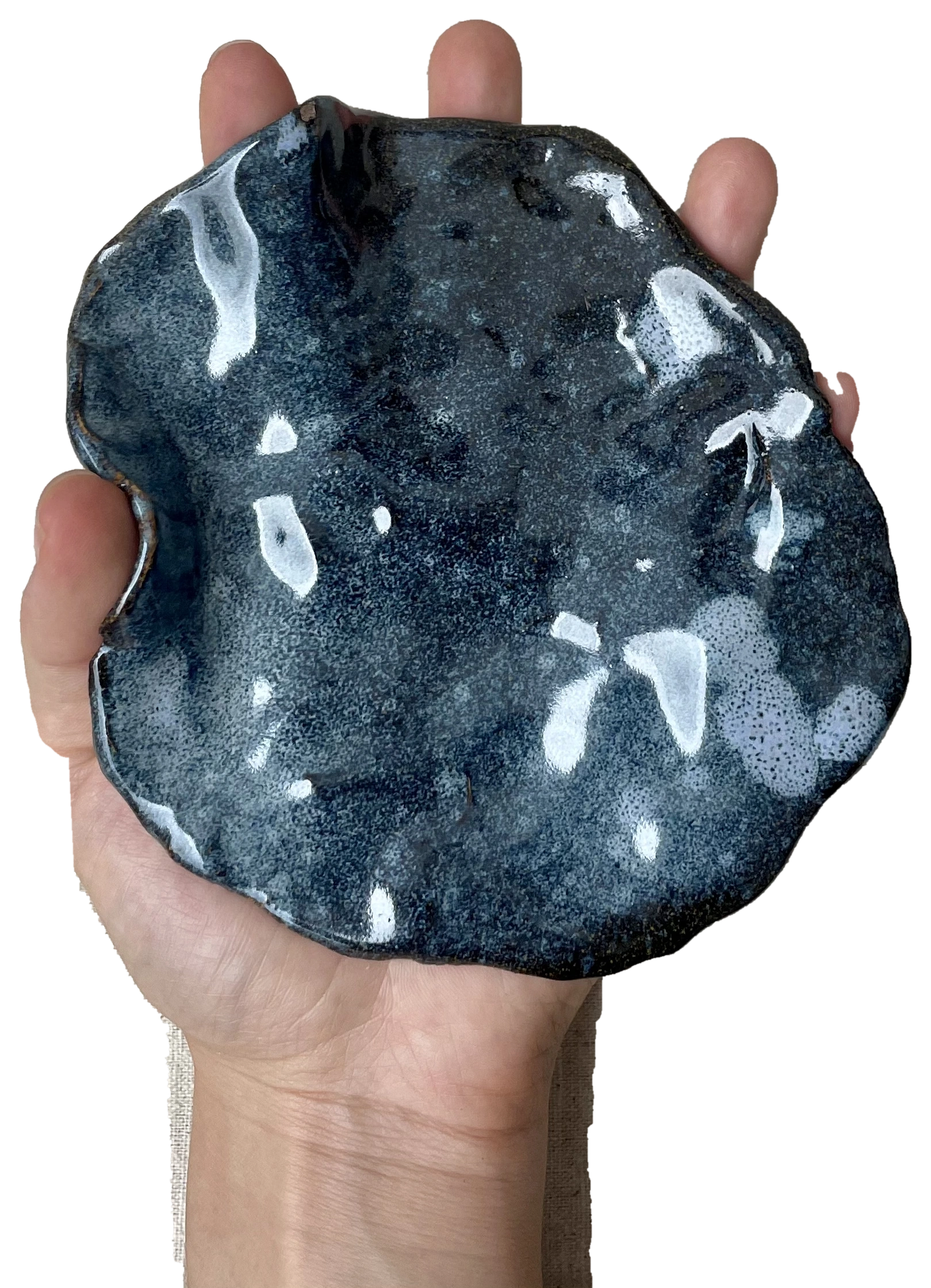 A hand and forearm holding a dark blue irregular ceramic dish