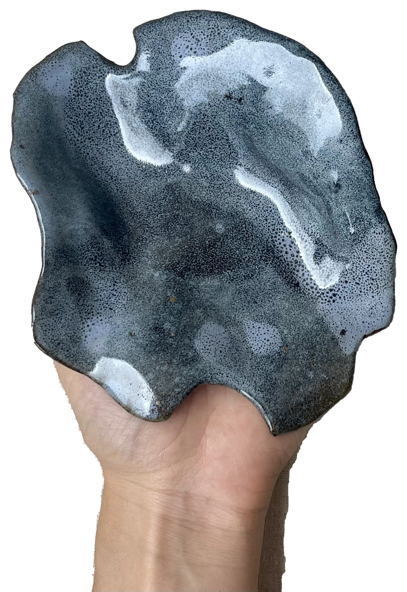 A hand and forearm supporting a blue-grey sculptural ceramic form