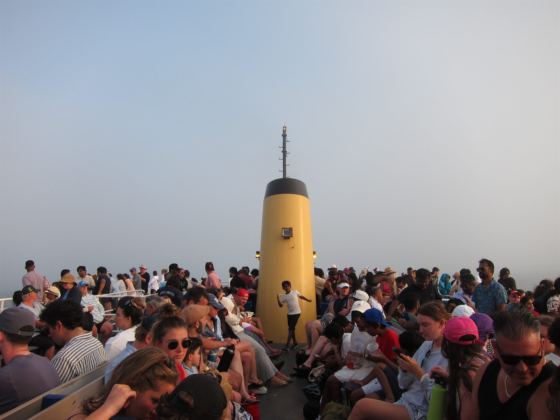 Crowd of passengers gathered on a ferry sun deck under open sky