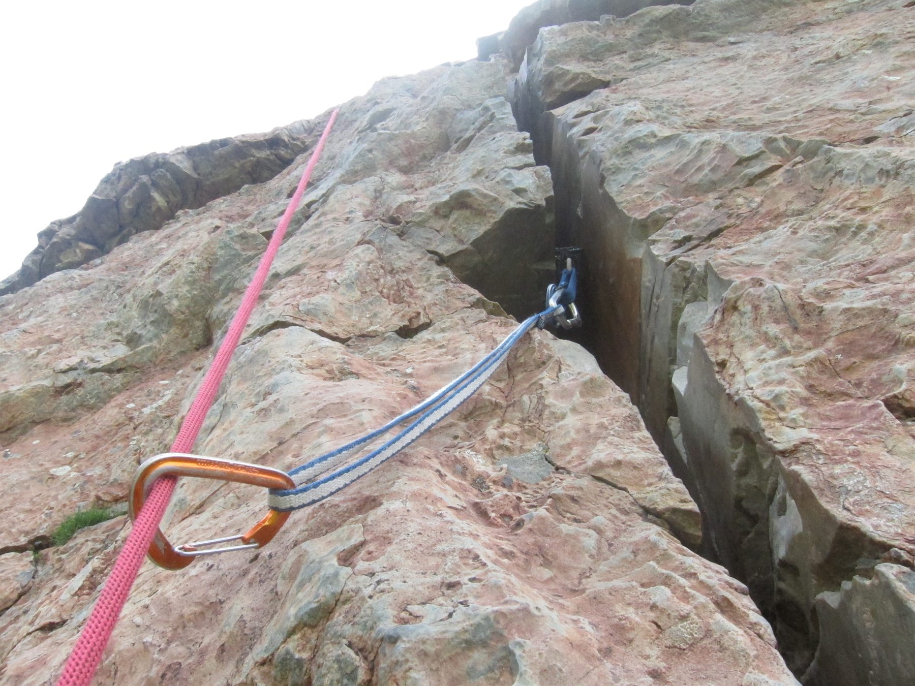 Spring-loaded camming device seated deep within a granite split with sling and carabiner