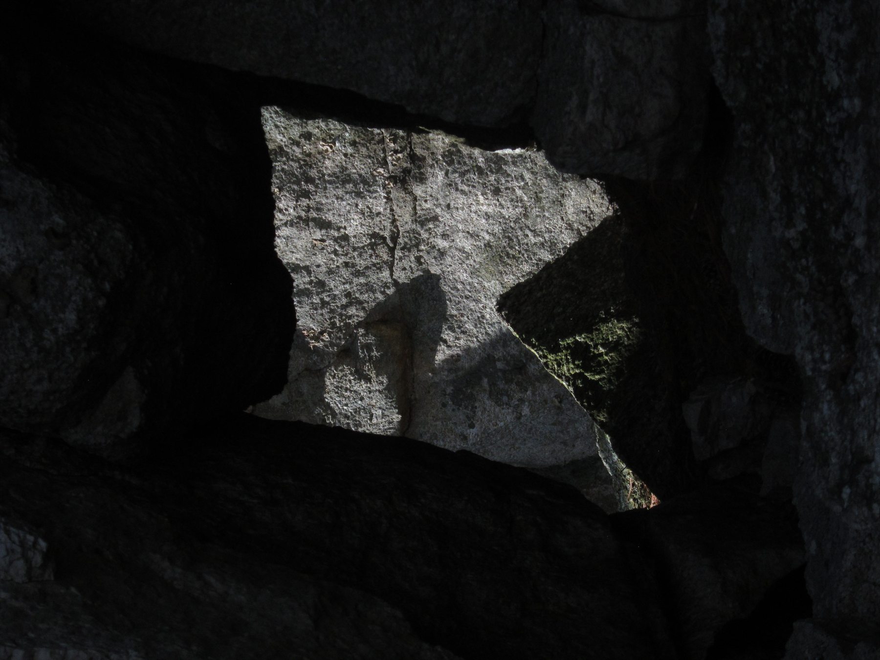Sunlight illuminating textured granite through a natural aperture